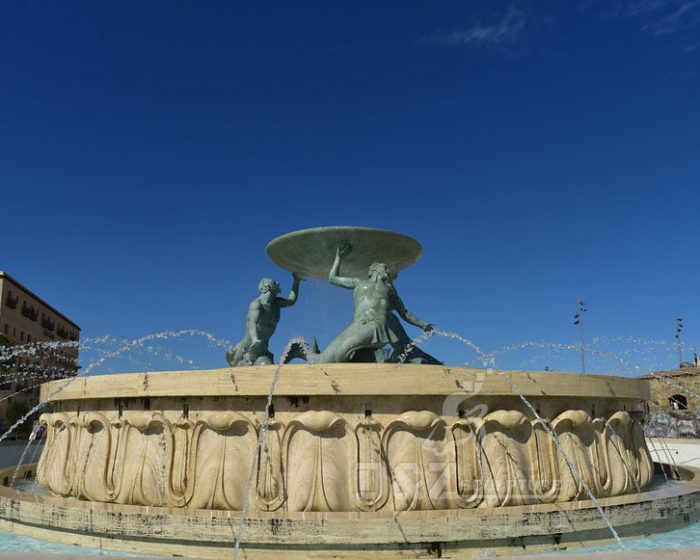 bronze Triton statues support a big bowl water fountain