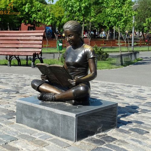 Bronze girl sitting and reading book statue in the park DZB-163